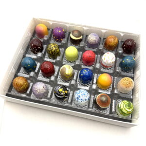 A twenty four piece box of hand-painted Cacao Boys bonbons in every colour