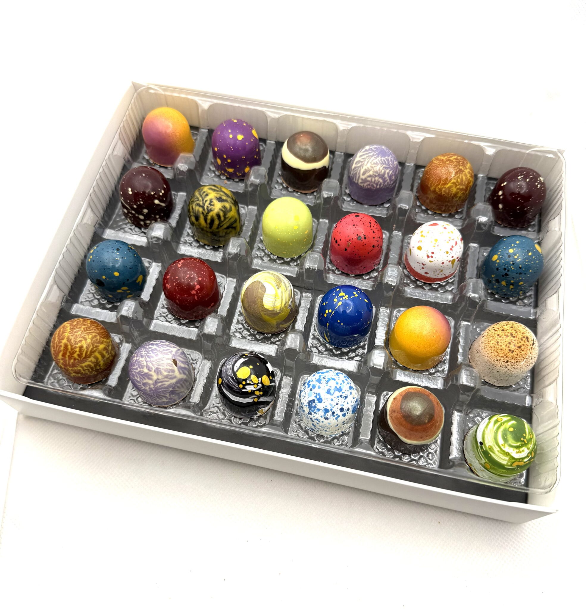 A twenty four piece box of hand-painted Cacao Boys bonbons in every colour