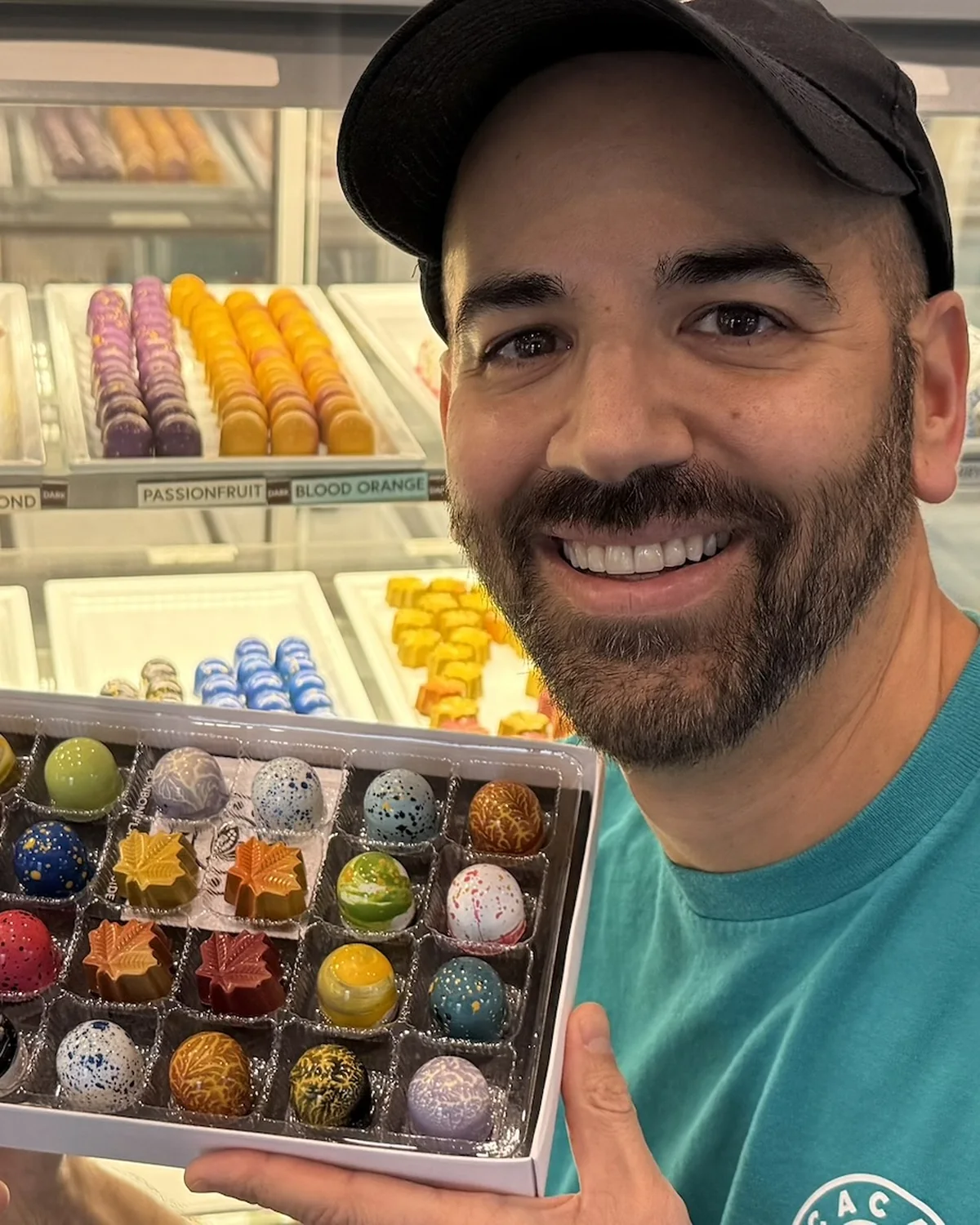 A Cacao Boys chocolatier holding a box of hand-painted bonbons in the Bala shop