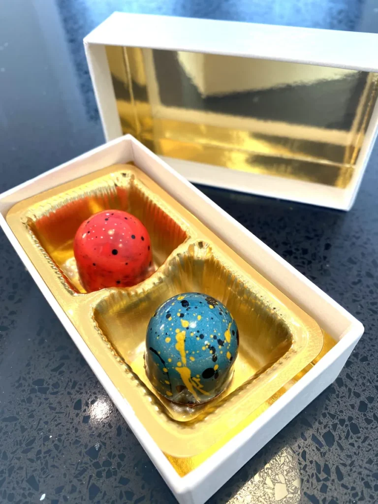 A two-piece Cacao Boys box holding a red and a blue hand-painted bonbon